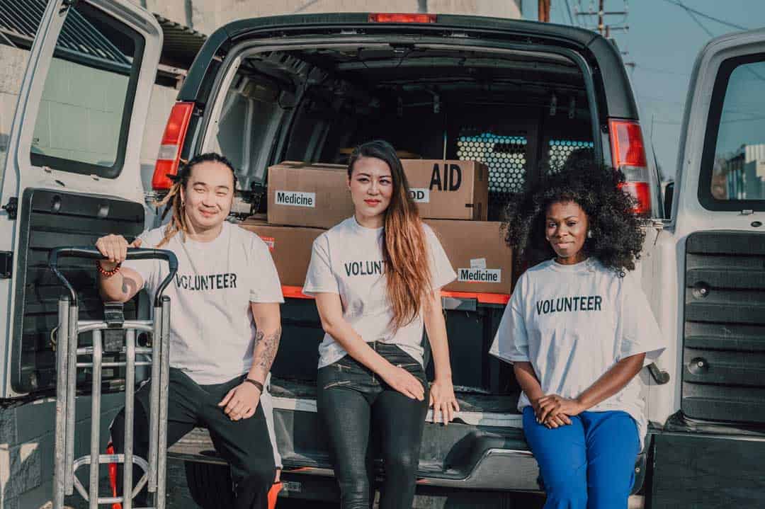 three volunteers sitting at the back of an open van